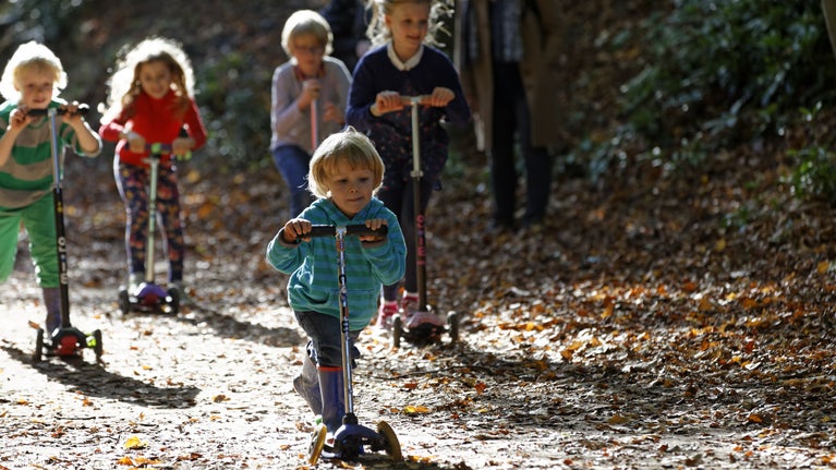 Children playing on scooters in the gardens at Cliveden, Buckinghamshire. Cliveden is nestled high above the River Thames with panoramic views over the Berkshire countryside.